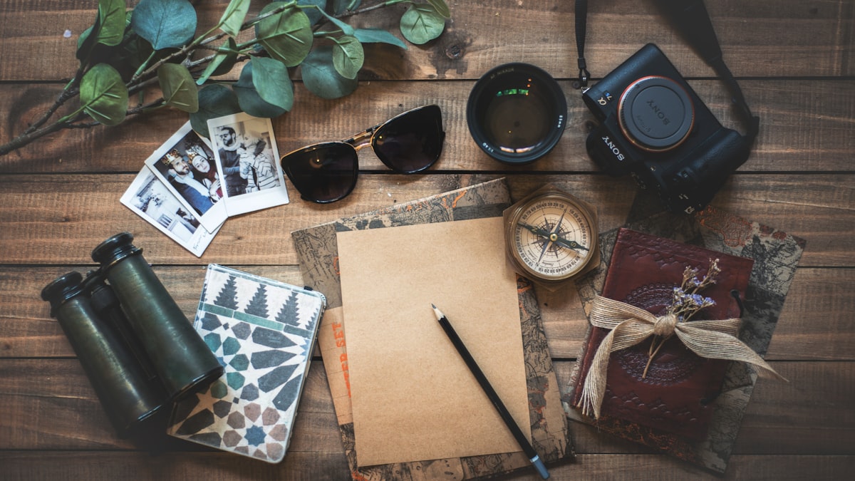 Caderno, câmera e objetos sobre uma mesa de madeira